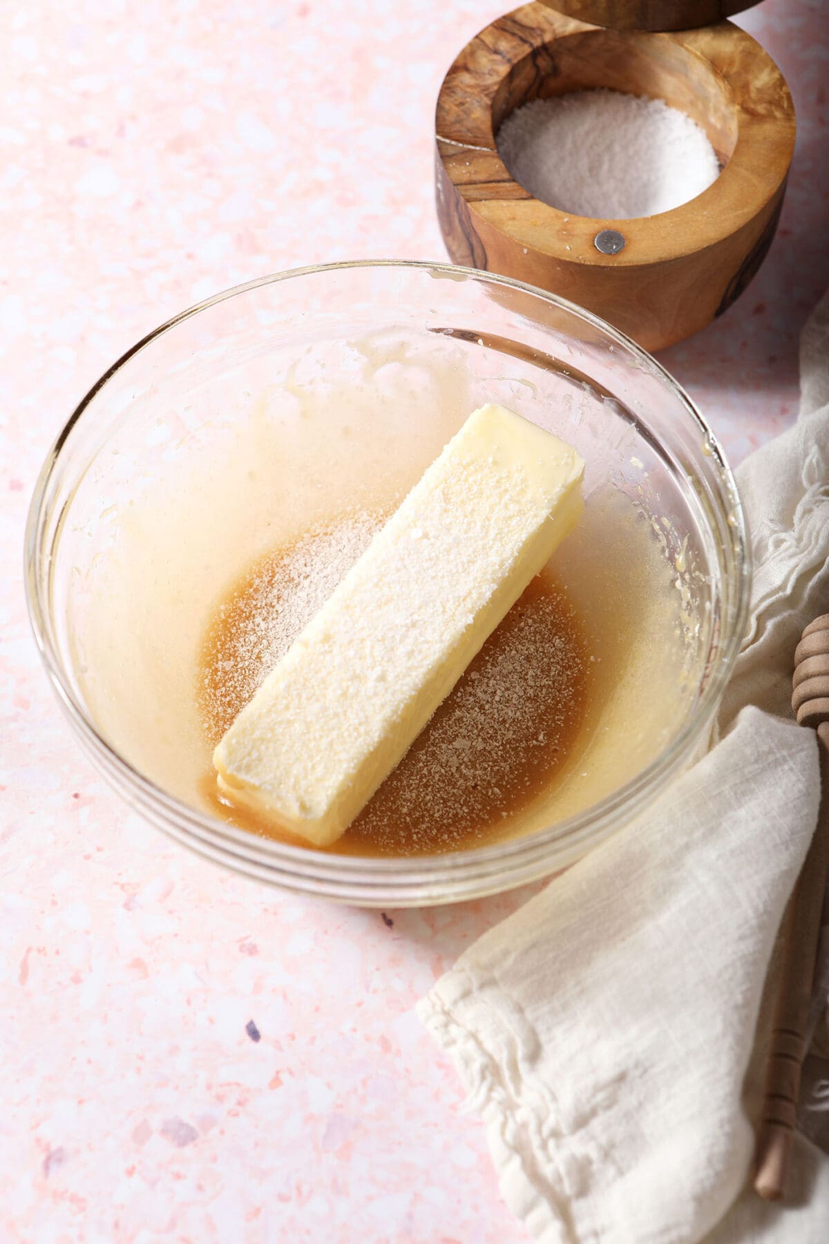 Butter on top of whipped honey with salt in a bowl on a pink surface