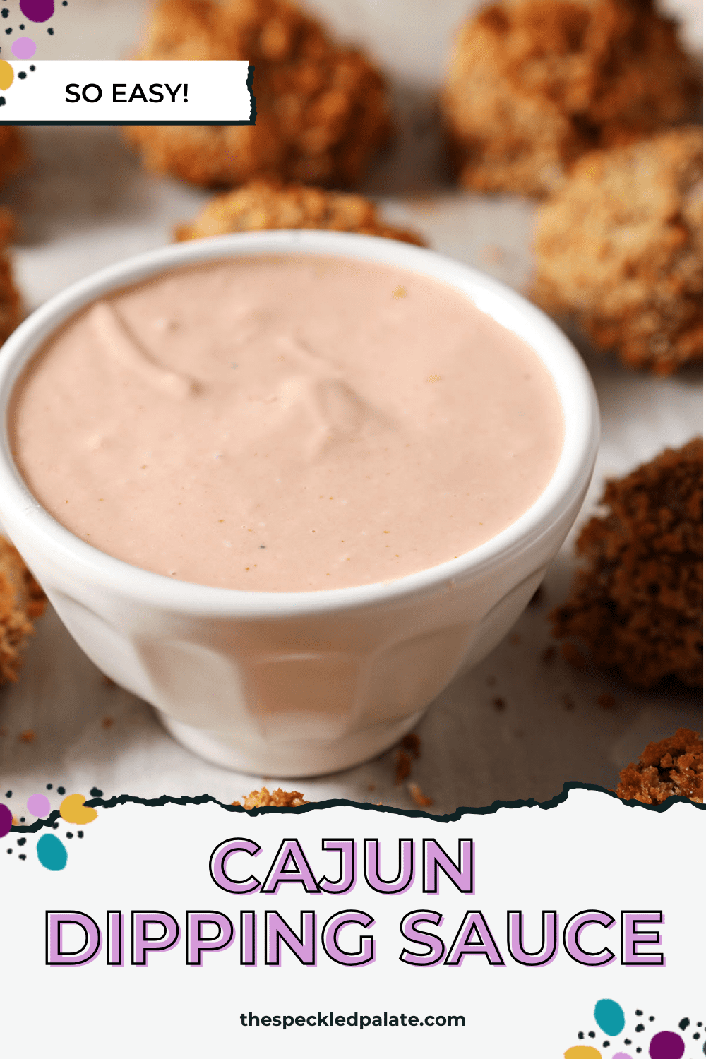 A bowl of Cajun Dipping Sauce surrounded by baked boudin balls on a sheet pan with the text cajun dipping sauce