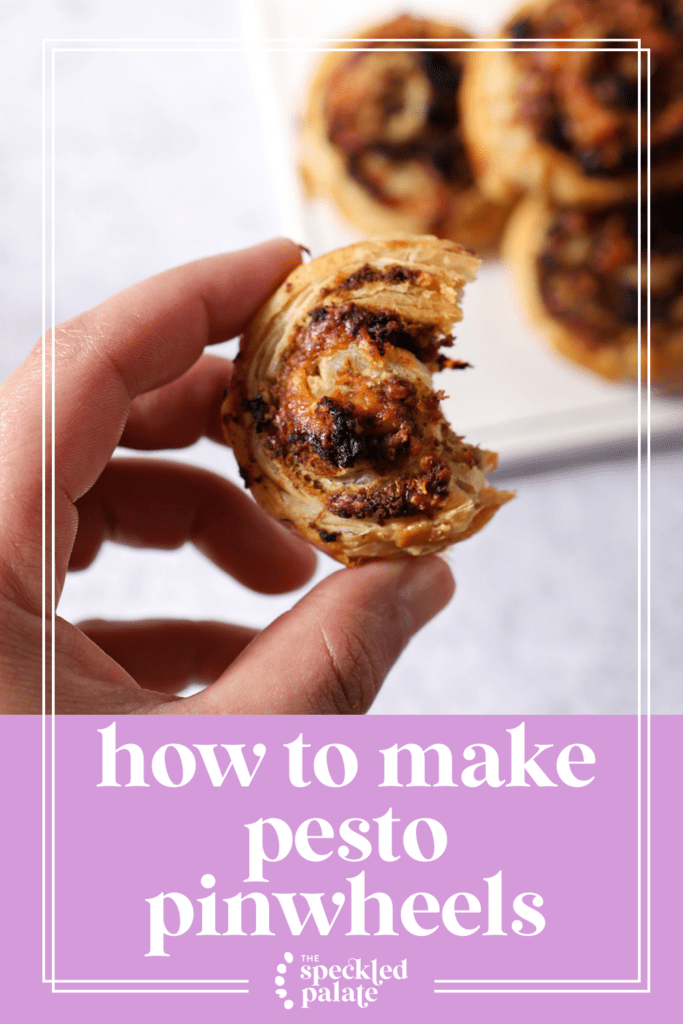 A hand holds a bitten-into pesto pinwheel above a white platter with the text how to make pesto pinwheels