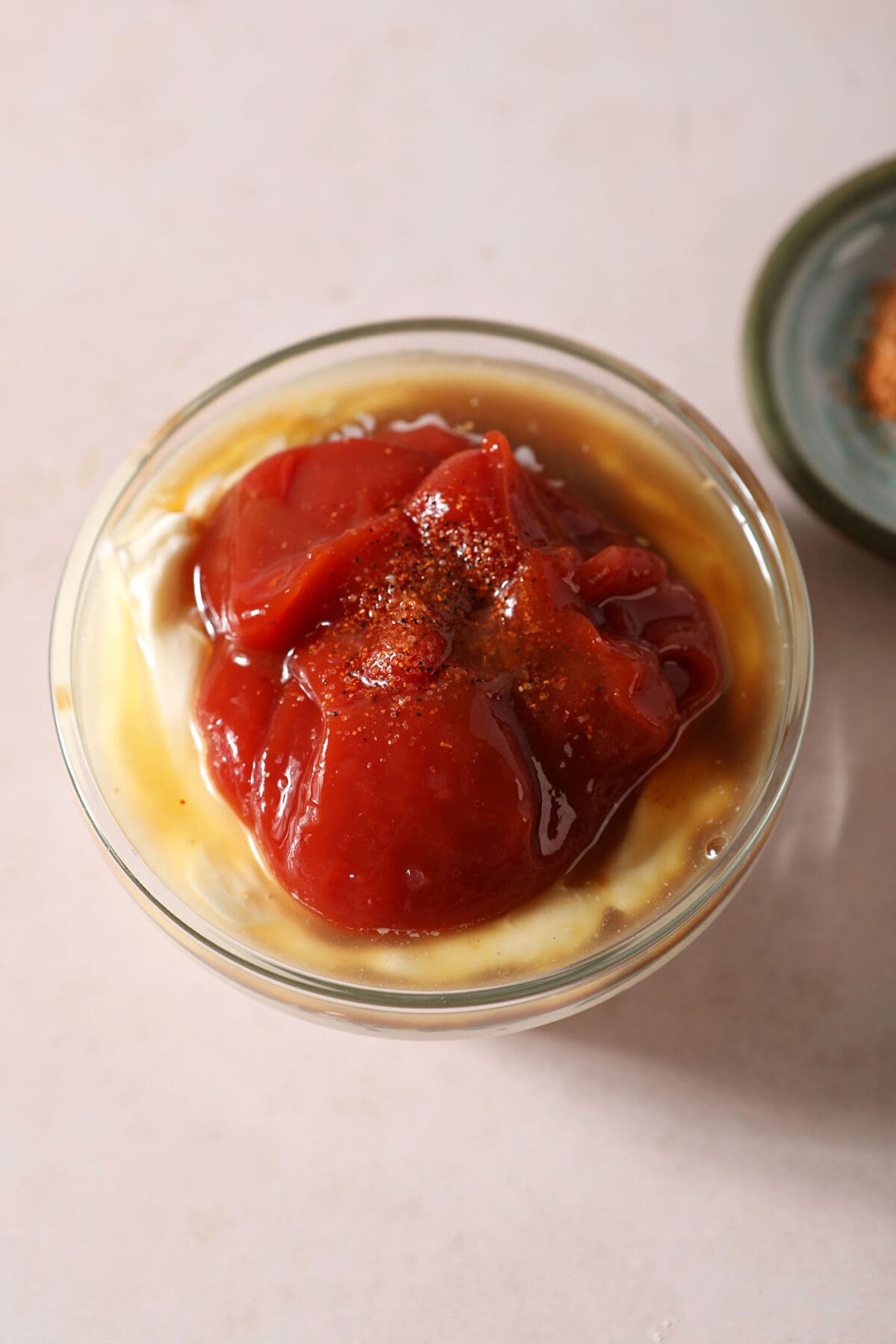 Cajun dipping sauce ingredients in a bowl from above on a taupe surface before mixing