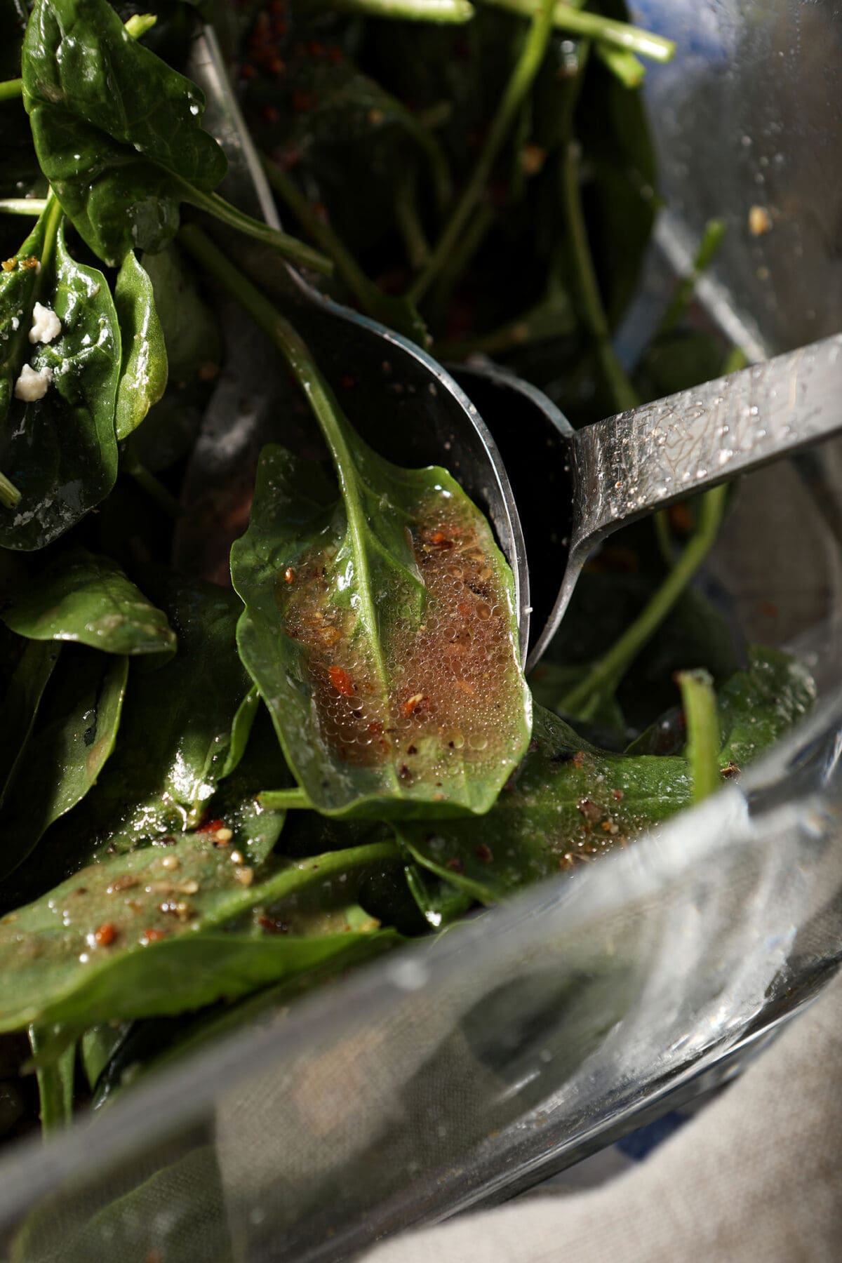 salad dressing on a fresh spinach salad before tossing
