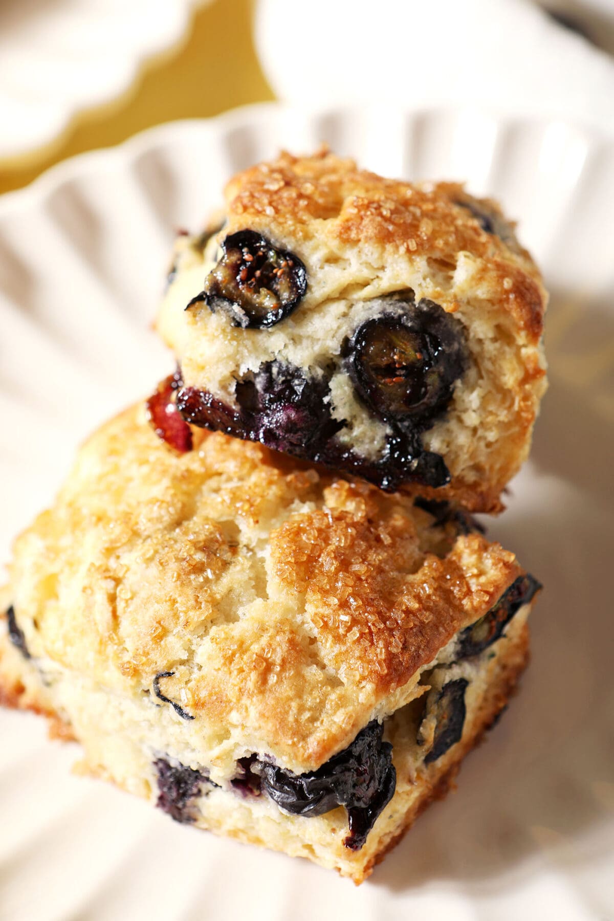 Two blueberry biscuits on a white scalloped plate