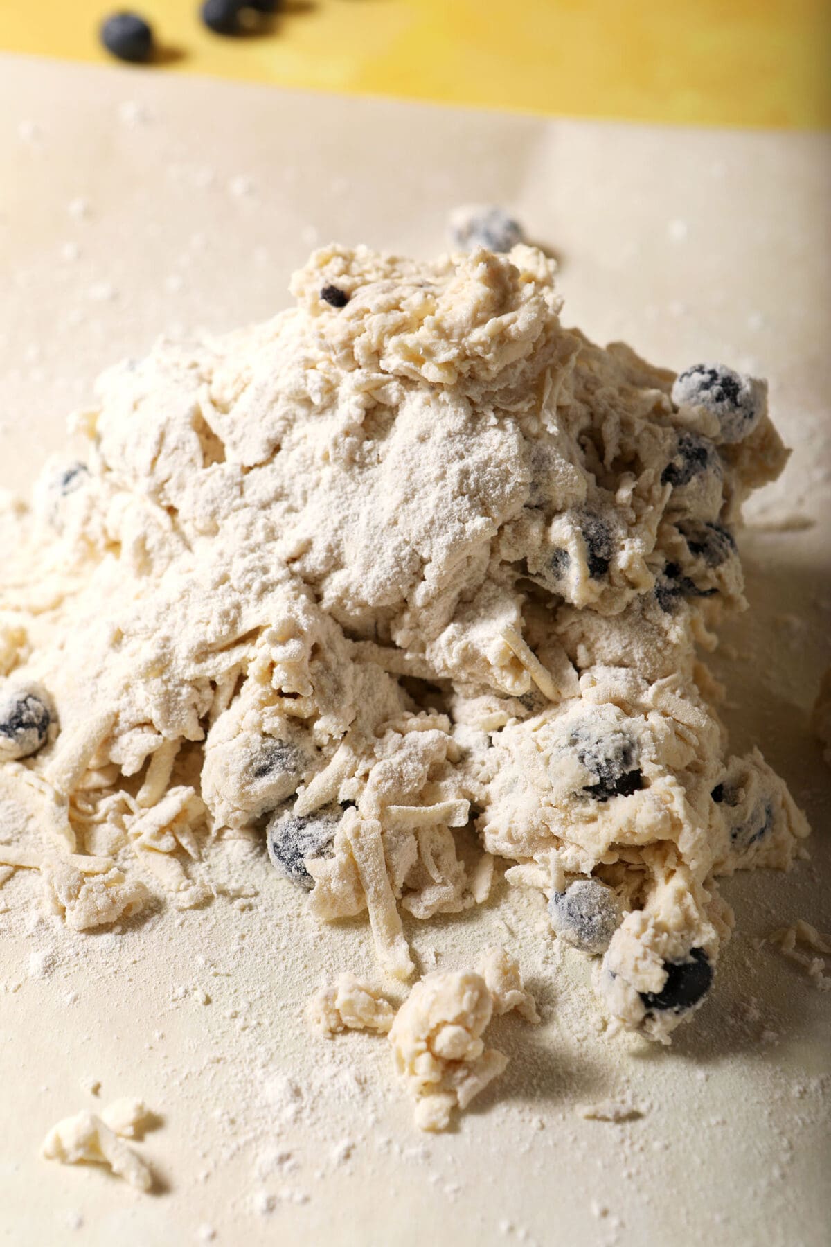 A shaggy biscuit dough on a floured parchment surface before shaping
