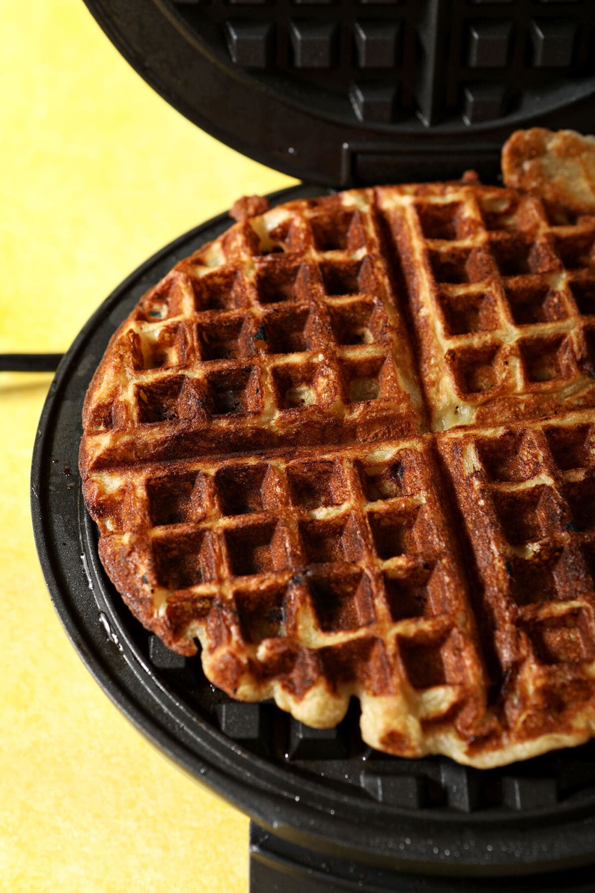 A banana waffle in a waffle iron, after cooking
