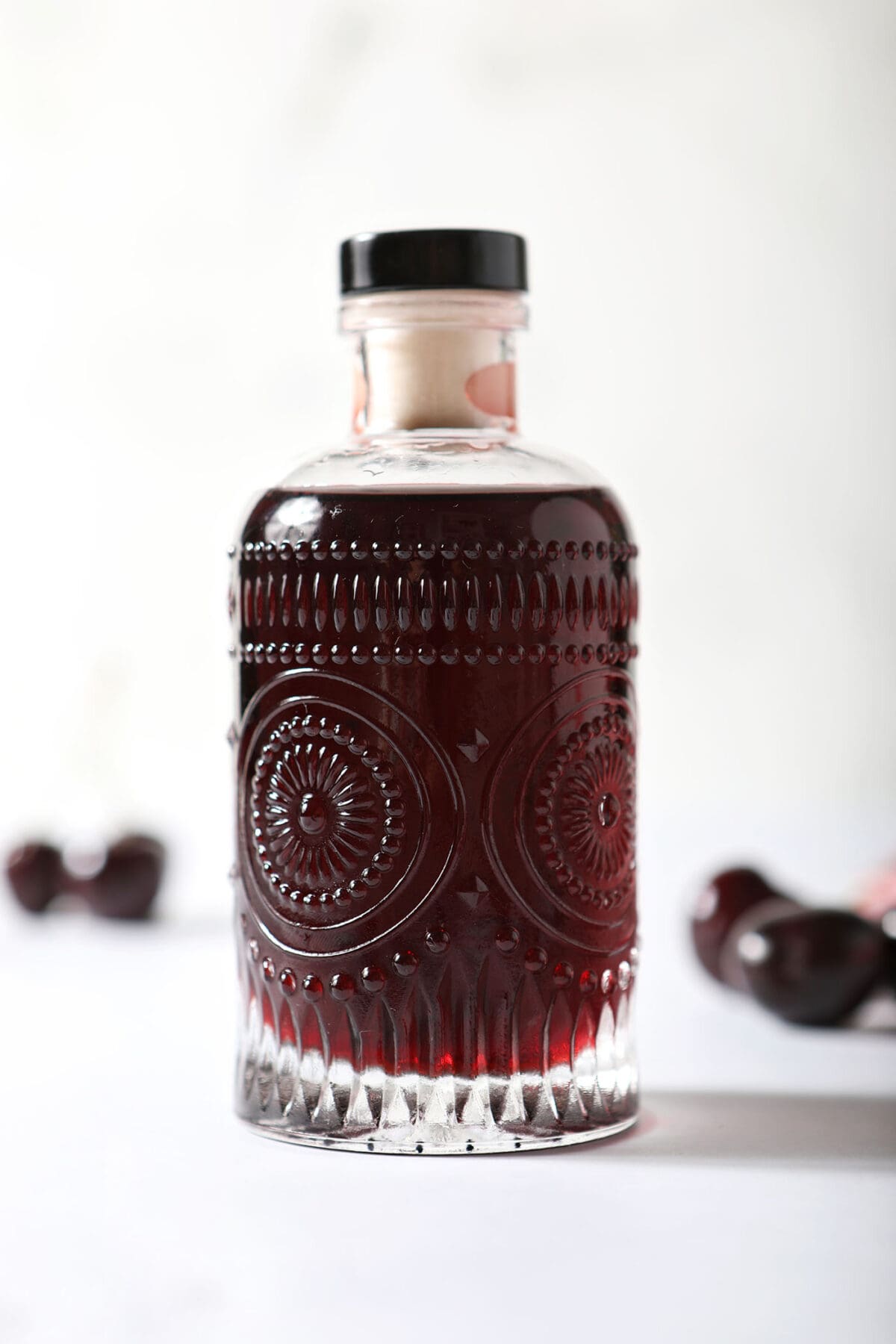 Close up image of a bottle of cherry syrup on a white surface