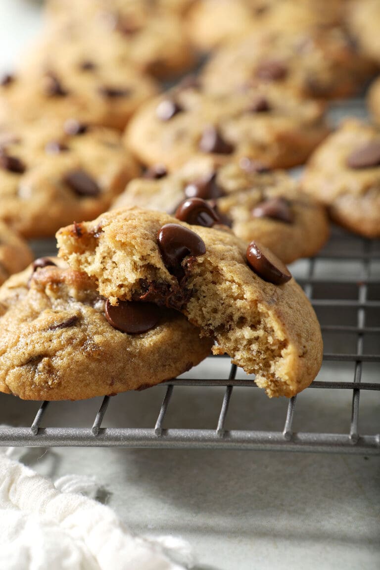 A cut into chocolate chip cookie with green chiles on a wire rack