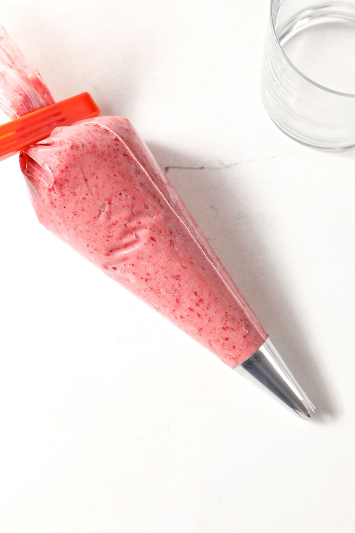 A piping bag of Strawberry Cream Cheese Frosting on a white stone surface