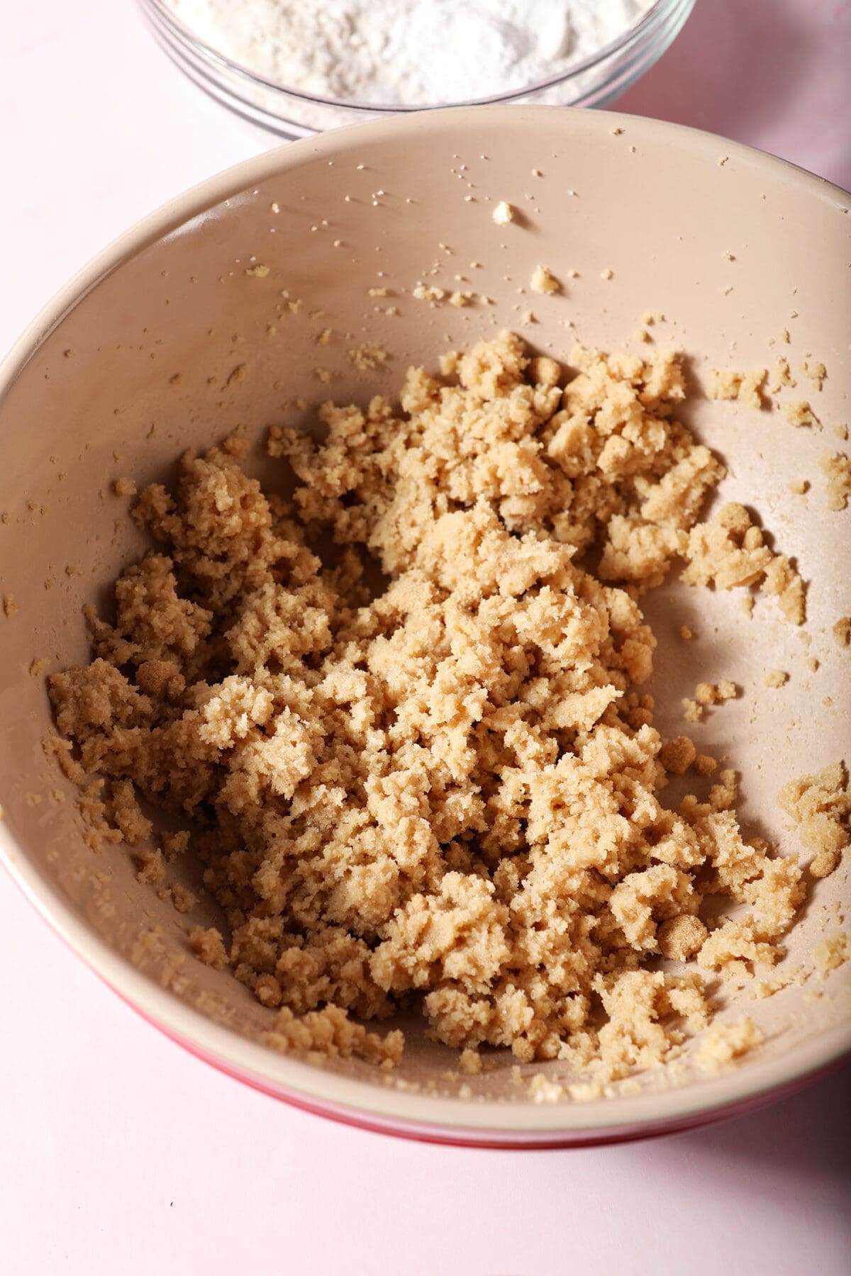 Creamed butter and sugars in a bowl on a pink surface