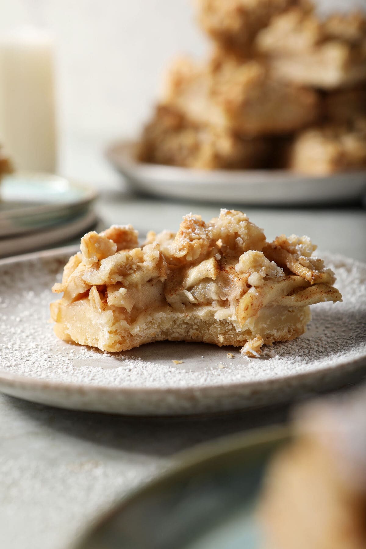 Close up of a bitten-into apple pie bar on a gray plate on a green surface