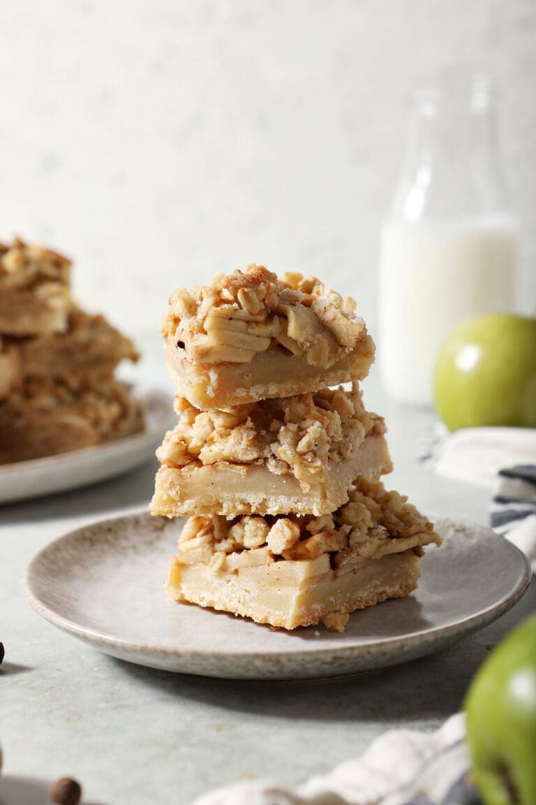 A stack of apple pie bars on a grey plate on a green surface