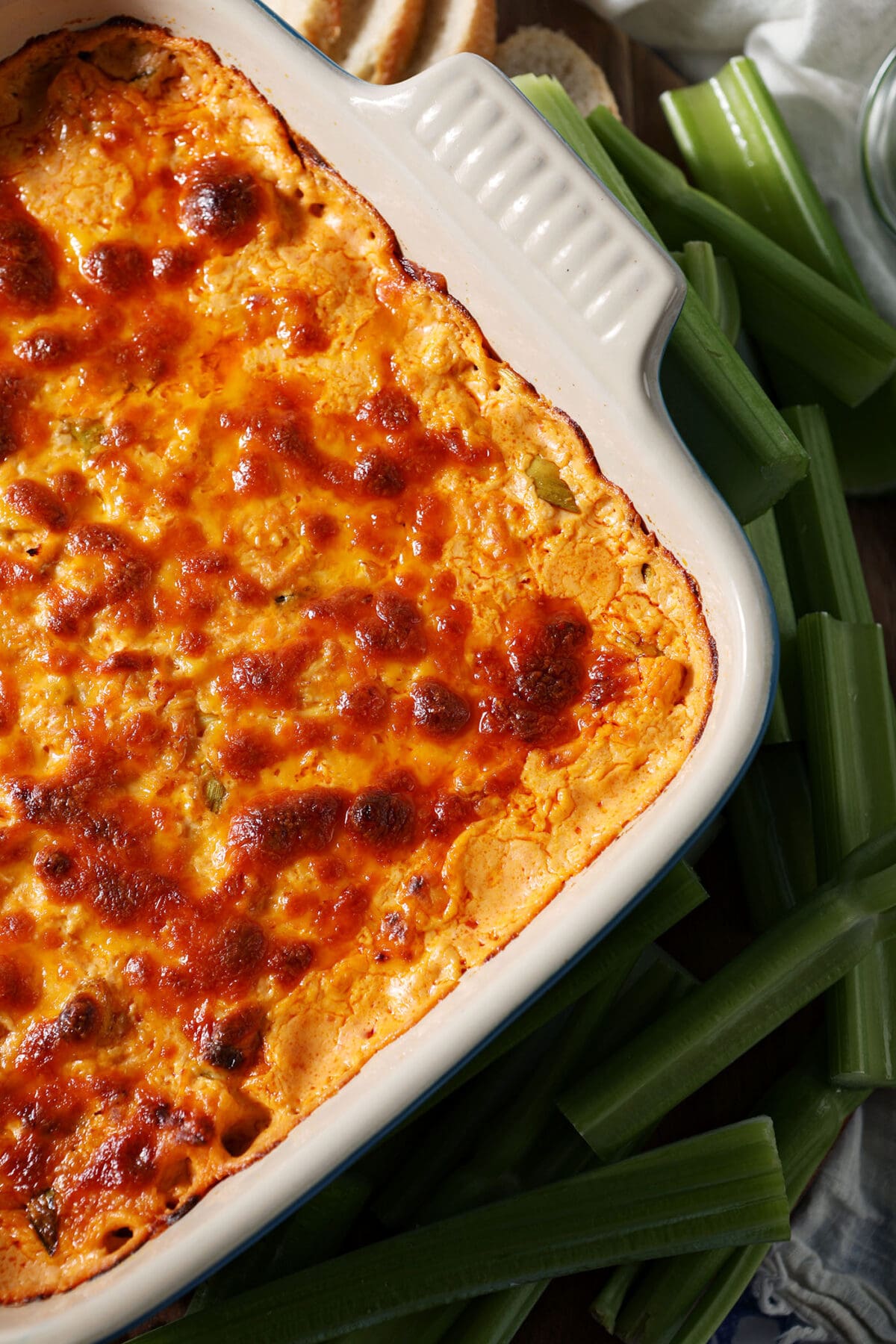 overhead of buffalo dip on a wooden board with celery and a sliced baguette