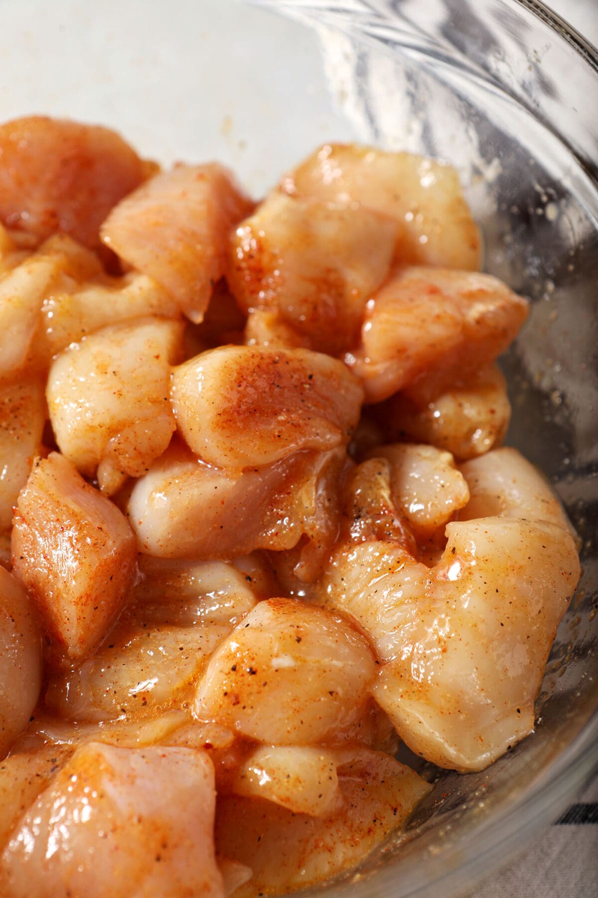 Close up of chicken breast chunks tossed in an egg wash in a bowl