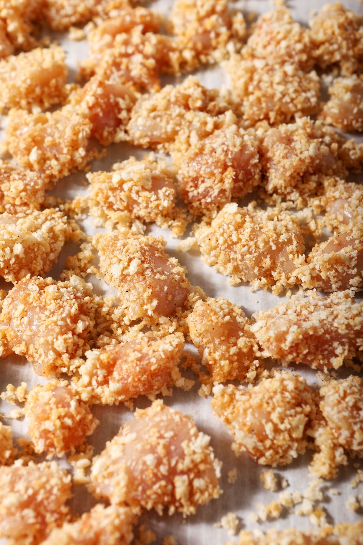 Breaded chicken on a parchment-lined sheet pan before baking