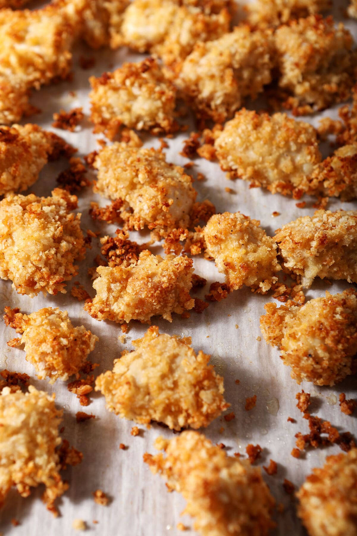 Baked chicken nuggets on a parchment-lined sheet pan