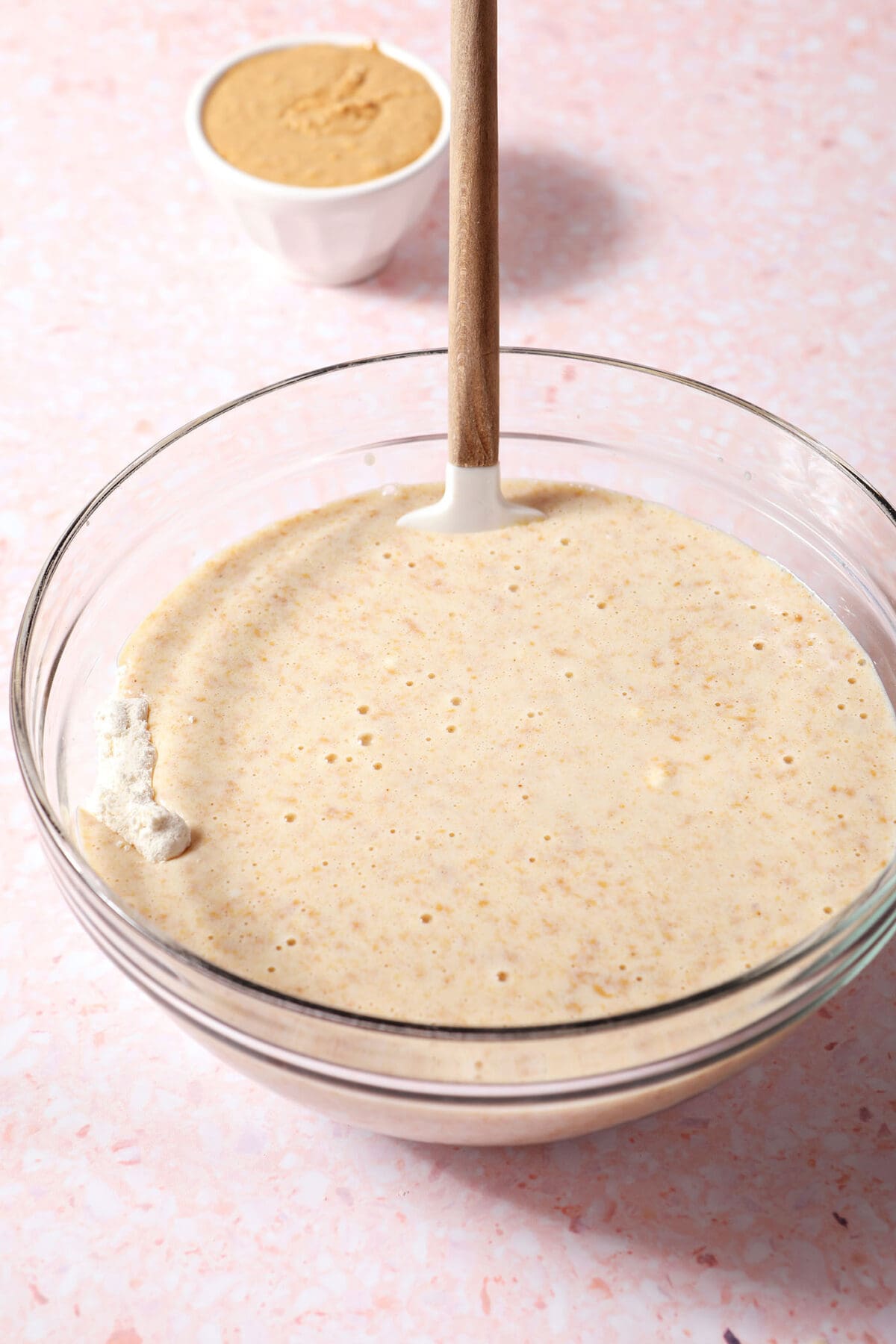 Wet ingredients sit on top of dry ingredients in a bowl on a pink surface