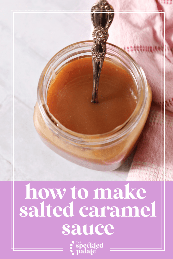 A mason jar of salted caramel sauce on a white tiled surface with a spoon inside it next to a pink linen with the text how to make salted caramel sauce