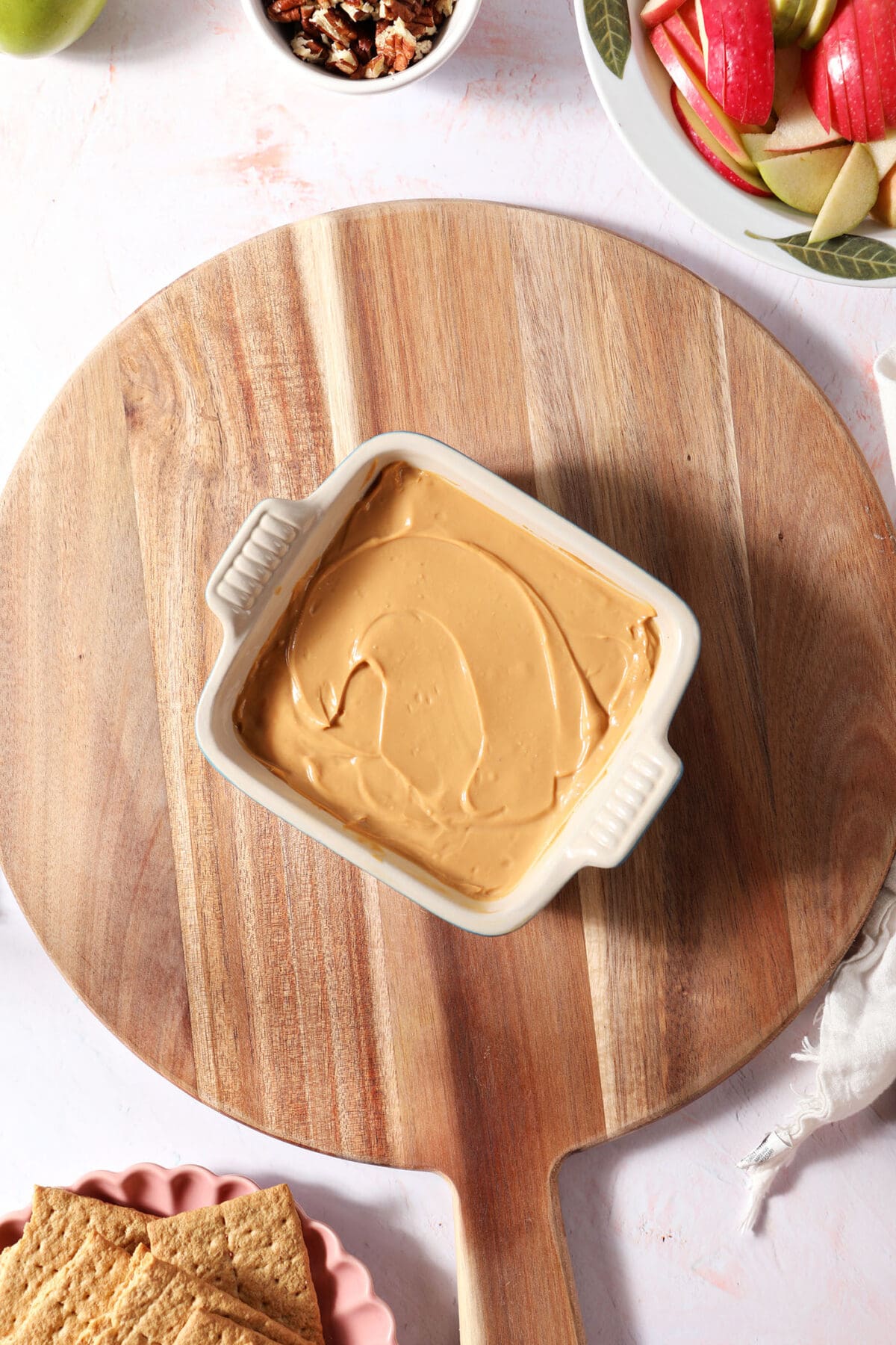 Caramel dip in a small serving dish on top of a wooden board