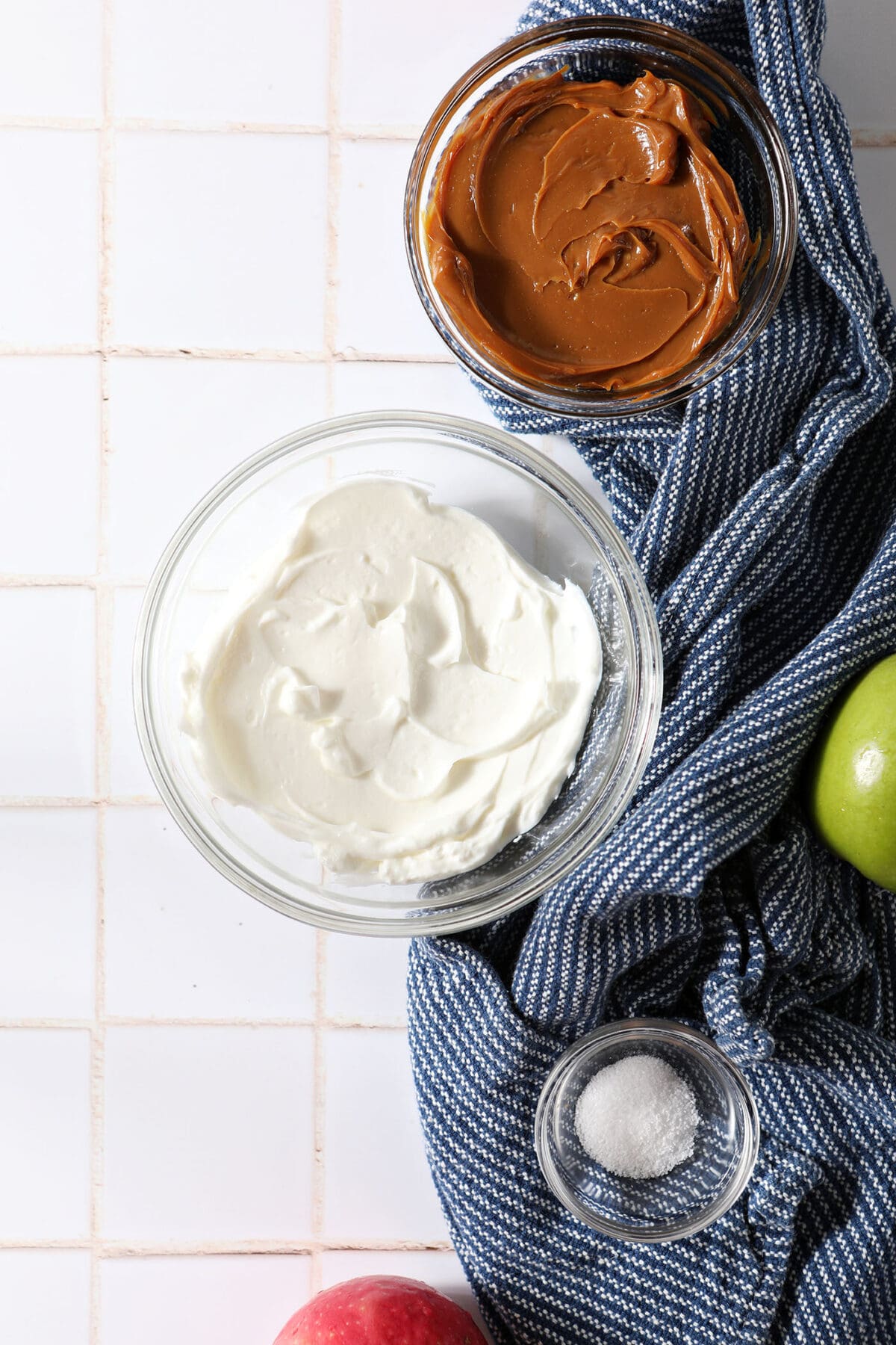 Ingredient to make Dulce de Leche Dip in bowls on a white tiled surface with a blue linen