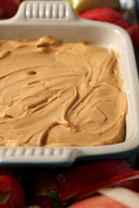 Side angle of caramel dulce de leche dip in a serving dish surrounded by apples