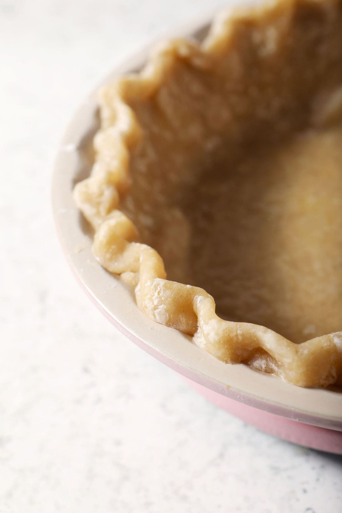 A par baked pie crust in a pink pie dish