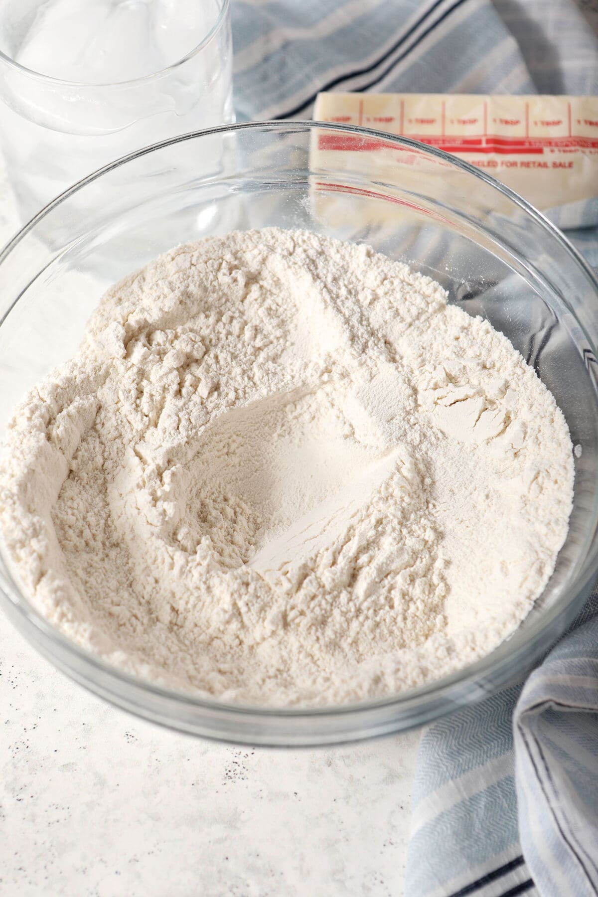 Dry ingredients in a bowl on a white surface with a blue striped linen
