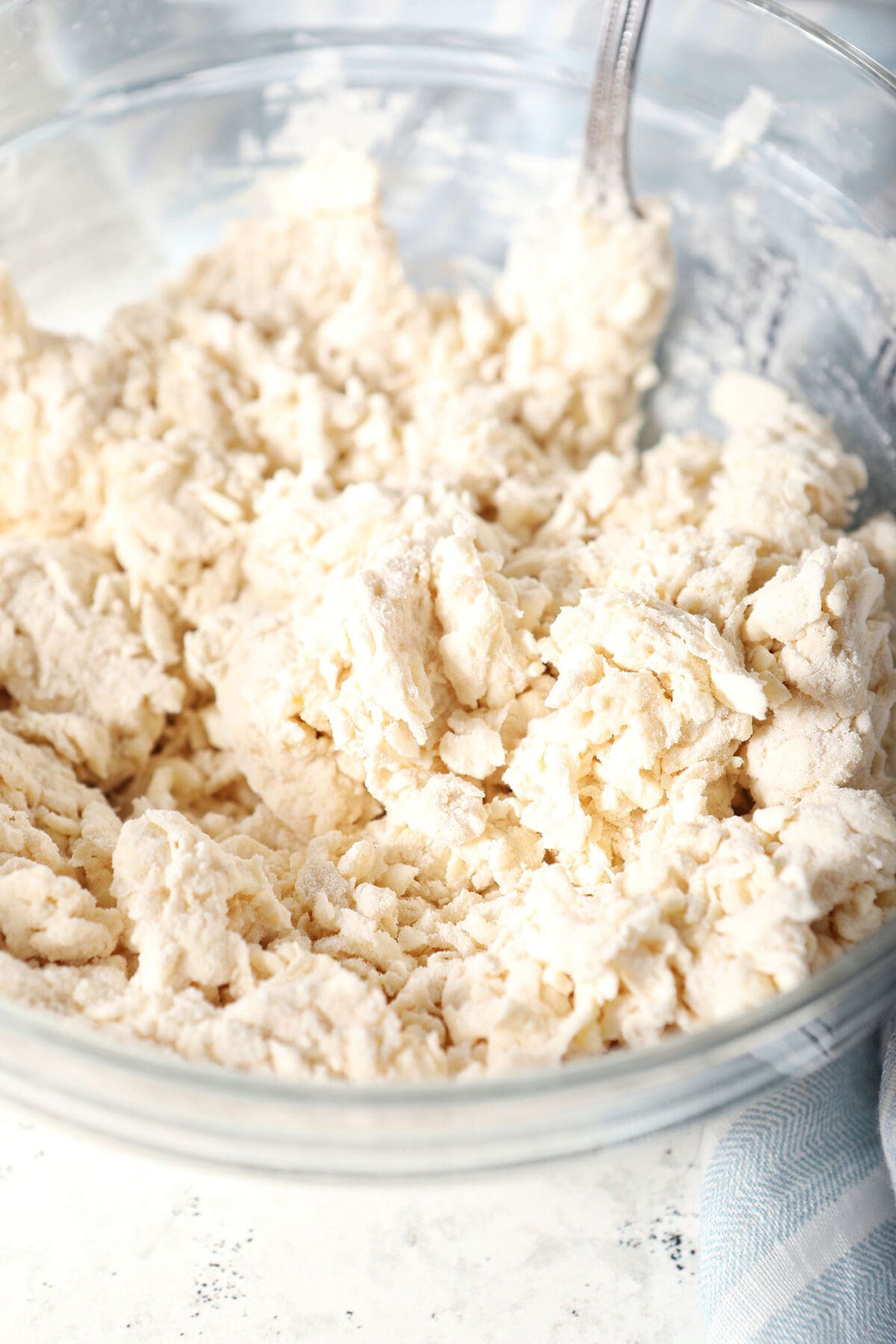 A crumbly pie crust in a bowl with a fork