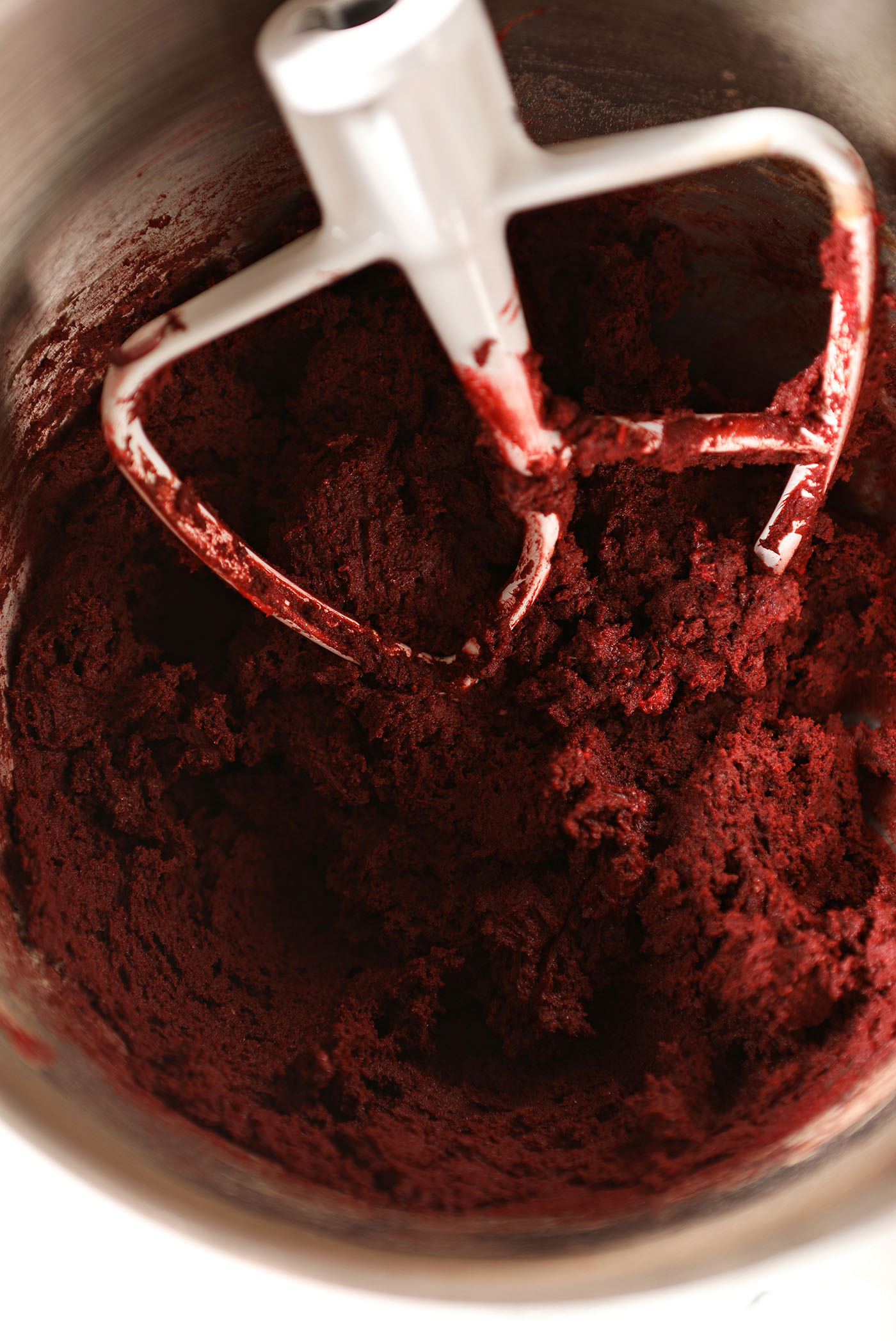 Red Velvet Cookie dough in a metal mixing bowl with the paddle attachment of a stand mixer