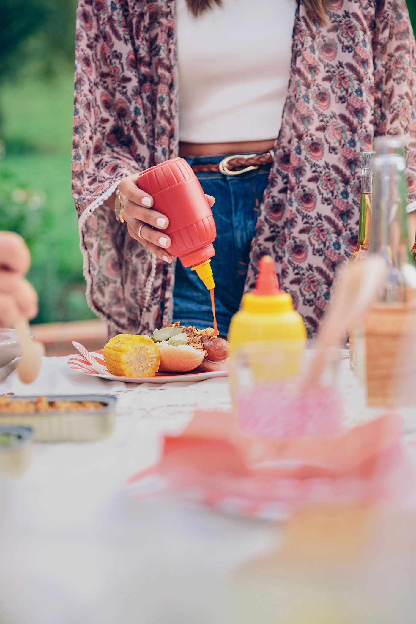 Woman hand pouring ketchup over an american hot dog