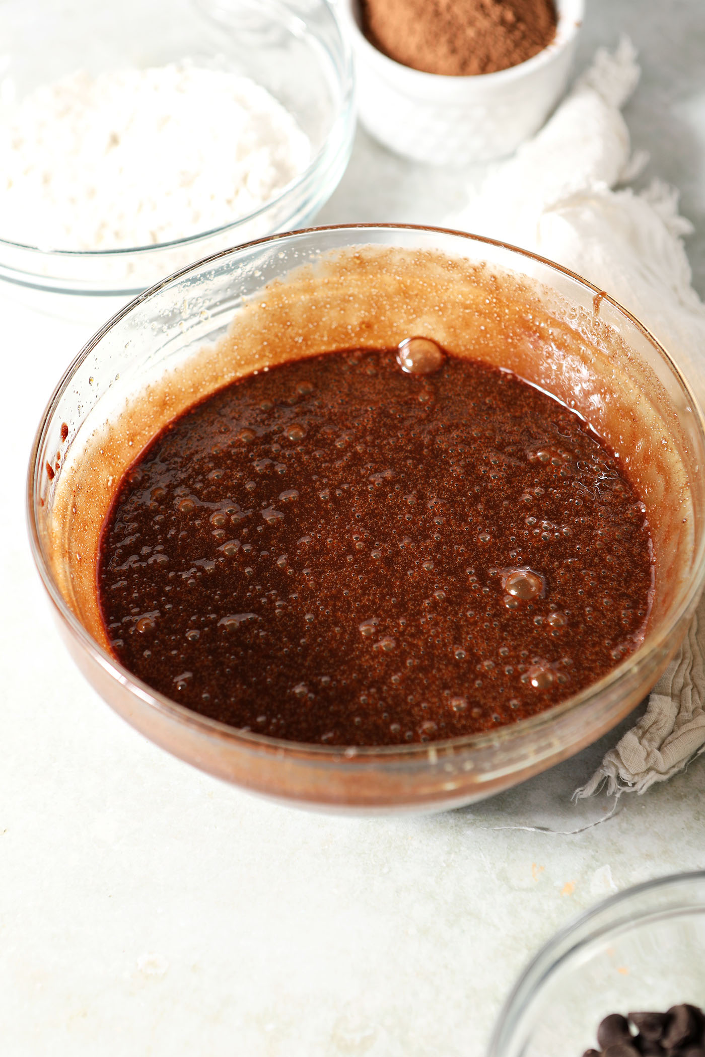 Wet ingredients for brownie batter in a bowl on a light green surface