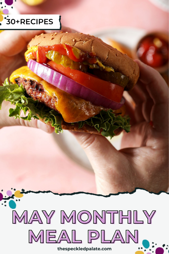 hands hold a burger over a pink surface with the text may monthly meal plan