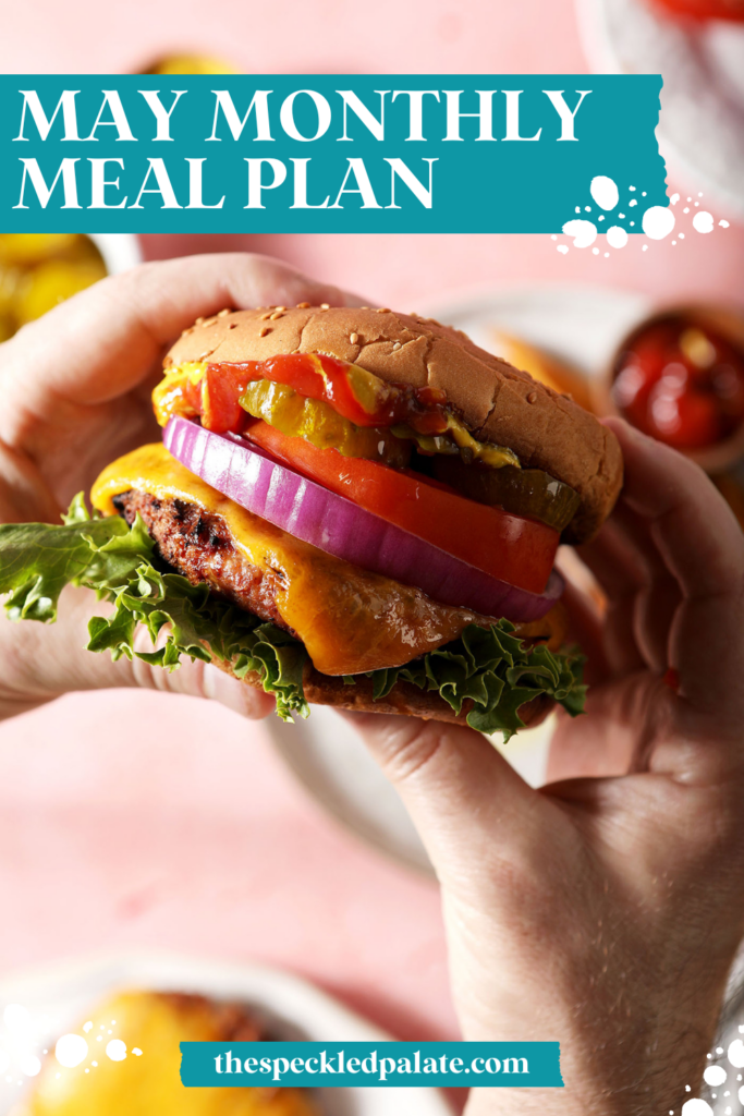 hands hold a burger over a pink surface with the text may monthly meal plan