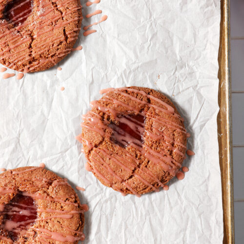Overhead of three Strawberry Lemonade Cookies on a cookie sheet after baking and frosting