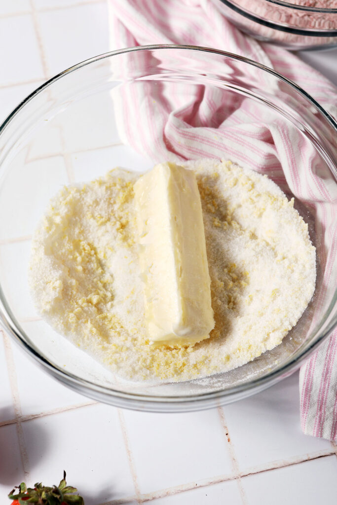 A stick of butter on top of lemon sugar in a bowl