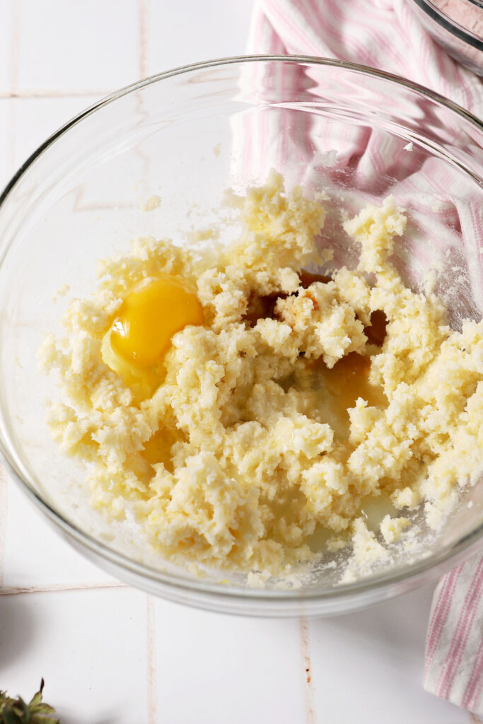 Egg, vanilla and lemon juice on top of creamed butter and sugar in a bowl before blending