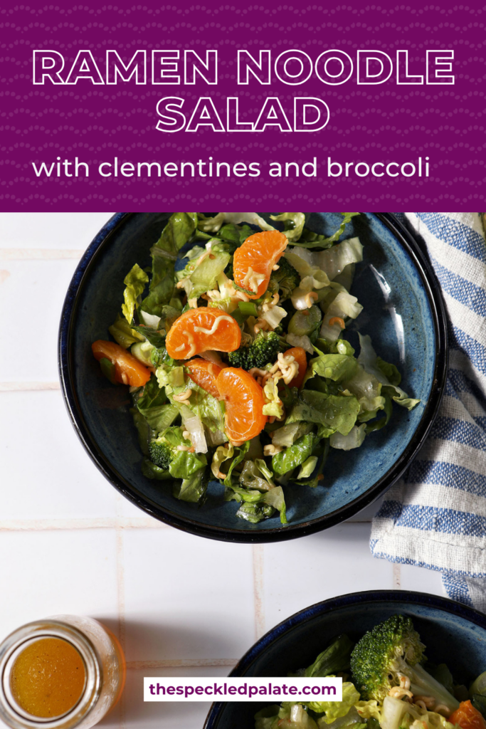 Close up of two blue bowls holding clementine ramen noodle salad with broccoli on a white tiled surface next to a blue and white linen with the text ramen noodle salad with clementines and broccoli