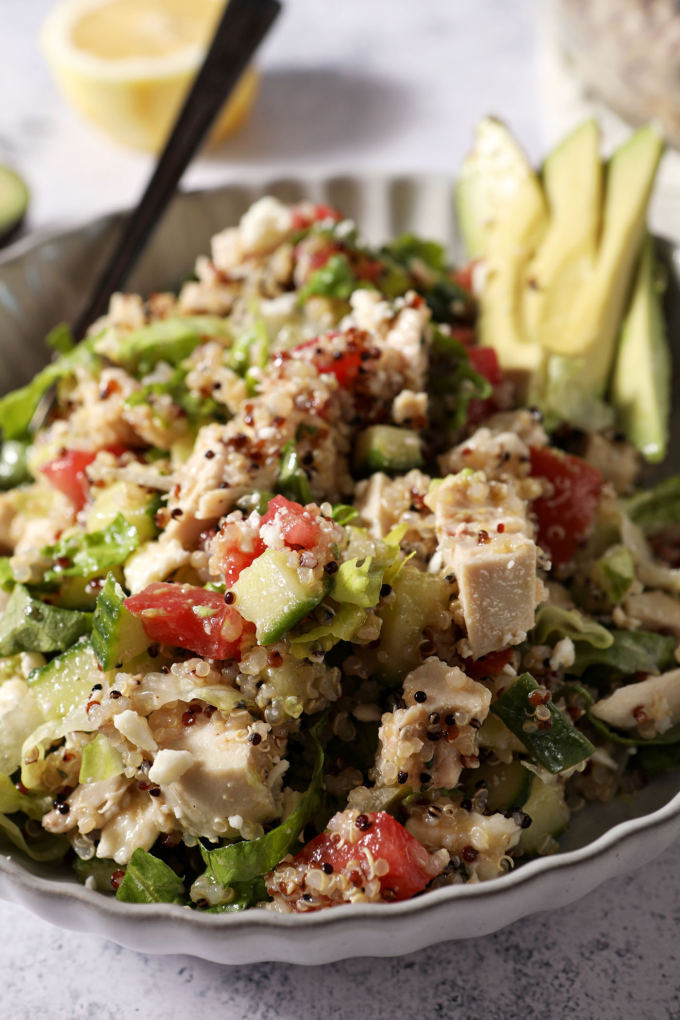 Close up of a Lemon Quinoa Salad with chicken in a bowl on a grey surface