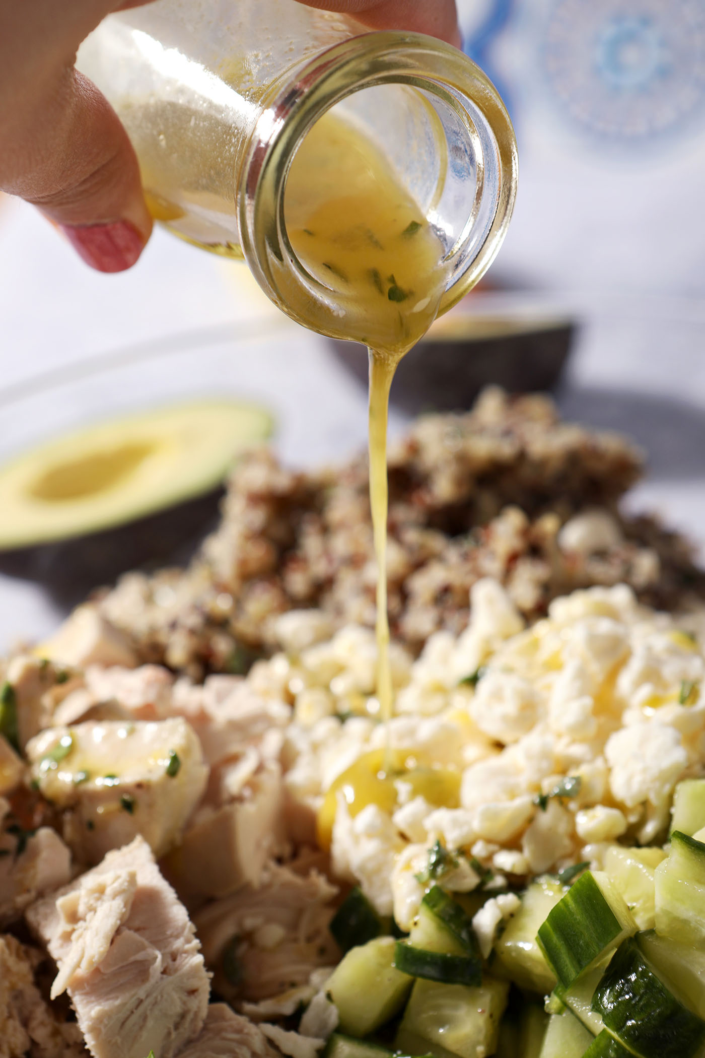 Lemon vinaigrette pours on top of a lemon quinoa salad with chicken