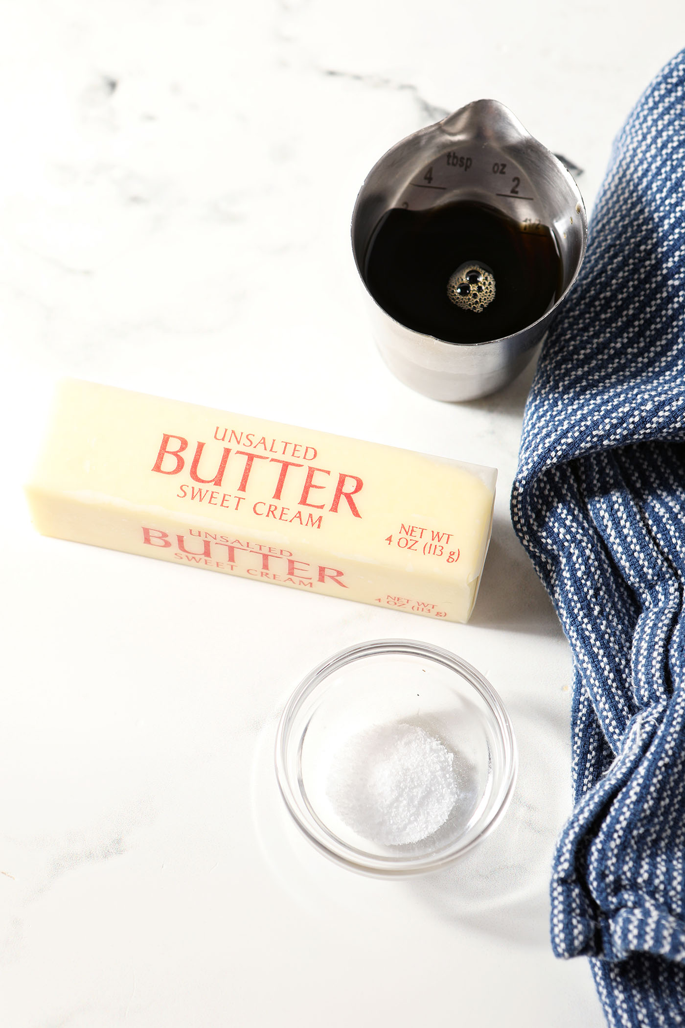 Ingredients to make homemade maple butter on a marble surface next to a dark blue linen