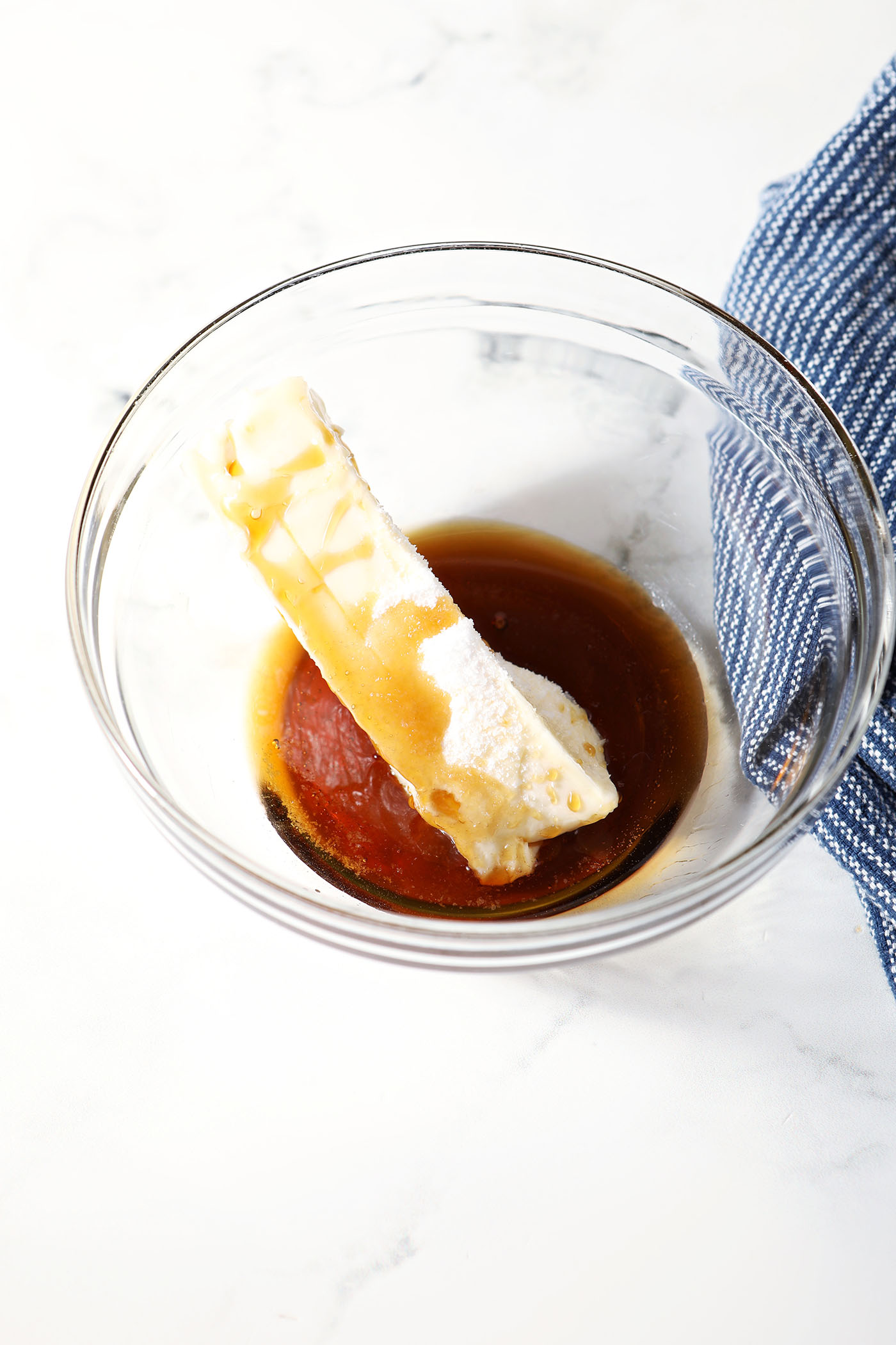 A stick of butter with salt and maple syrup in a bowl, before mixing