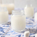 Three shot glasses of marshmallow vodka on a blue and white tiled surface