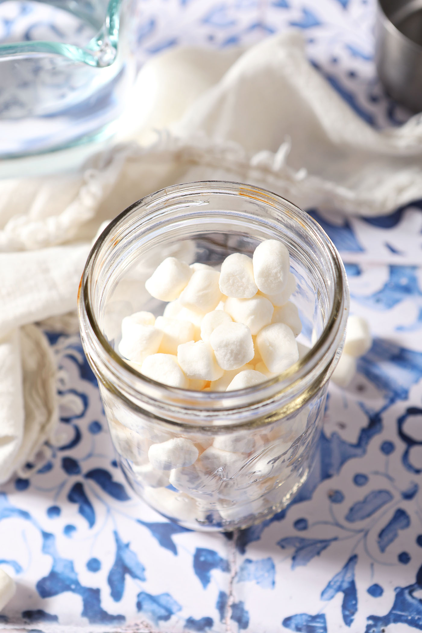 Marshmallows in a wide rimmed mason jar on a blue and white tiled surface
