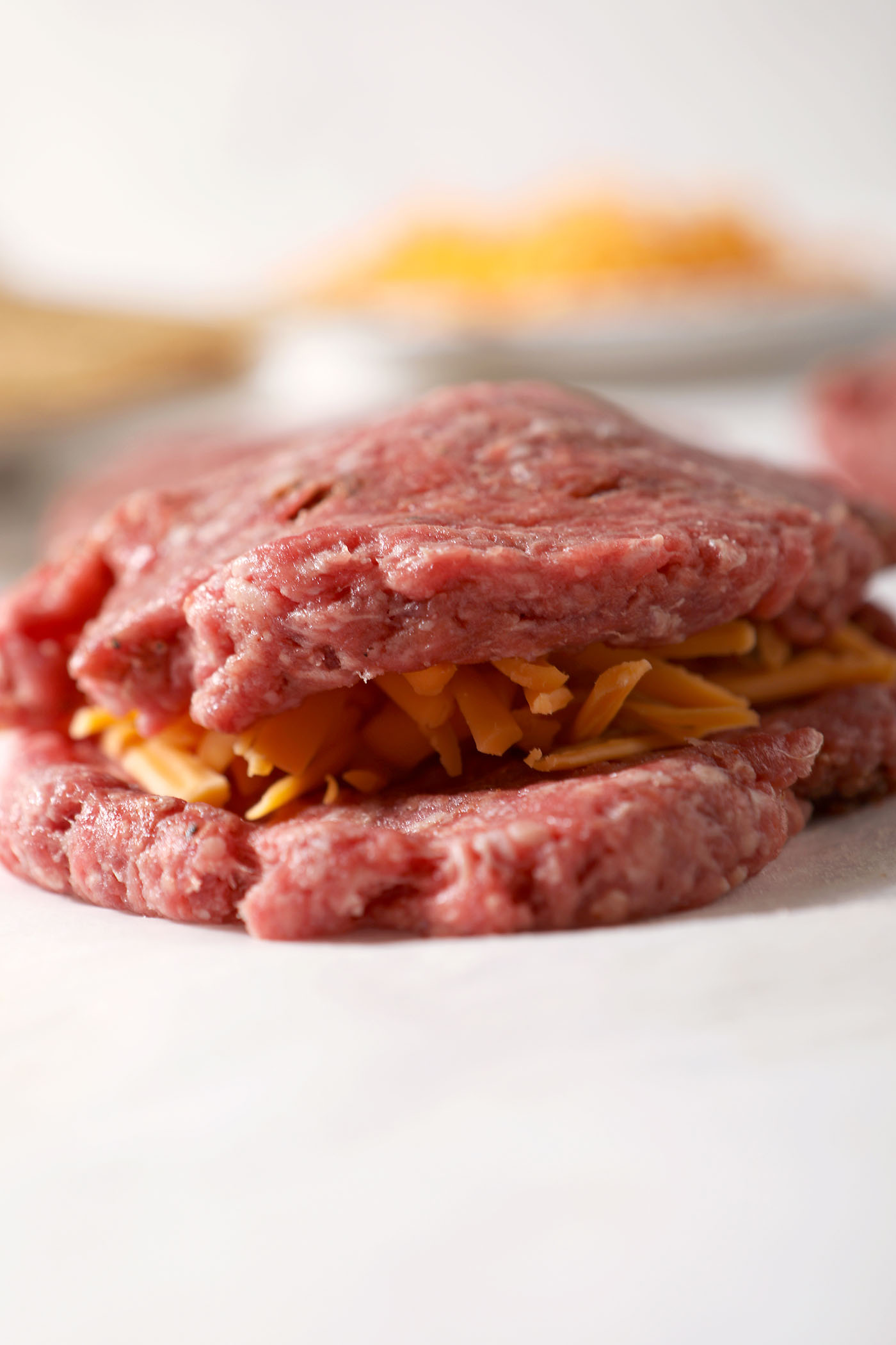 A juicy Lucy burger being assembled on a sheet of parchment
