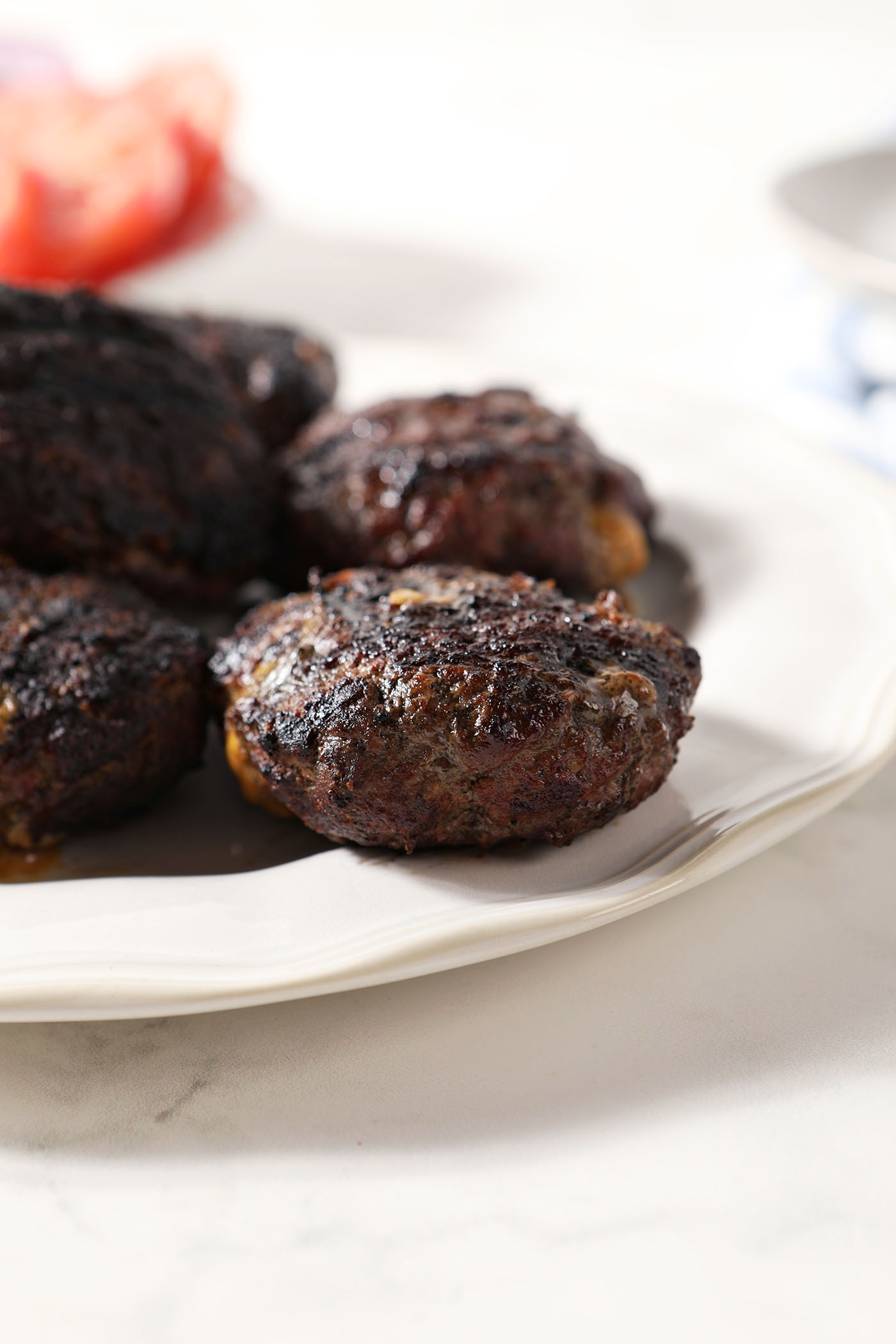 Grilled stuffed burgers on a white plate before assembling the burgers