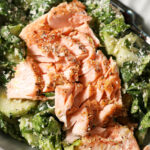Close up of a salmon caesar salad in a grey bowl from above