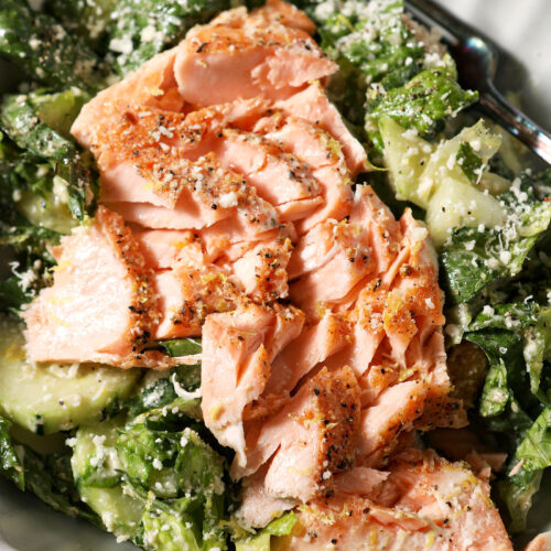 Close up of a salmon caesar salad in a grey bowl from above
