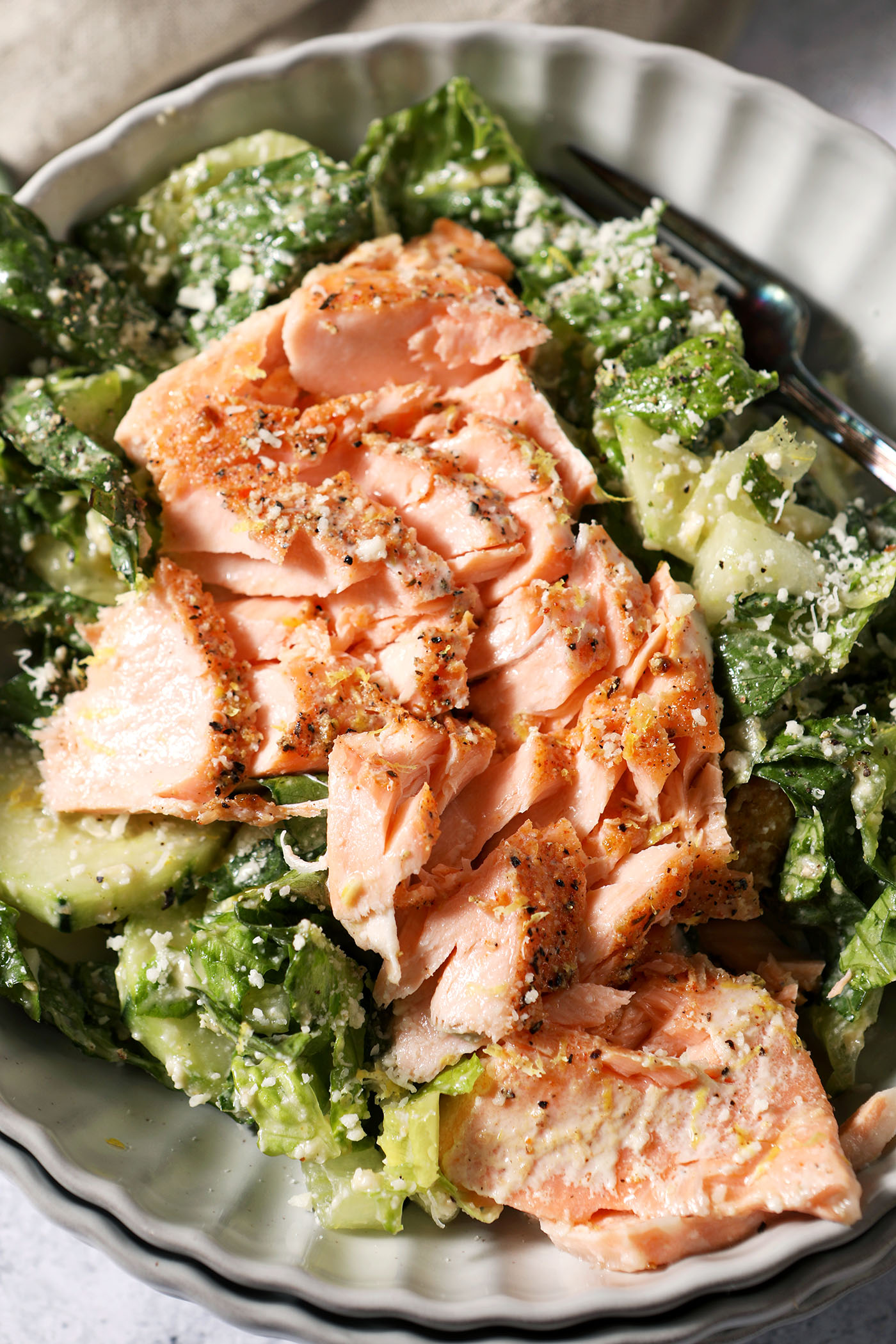Close up of a salmon caesar salad in a grey bowl from above