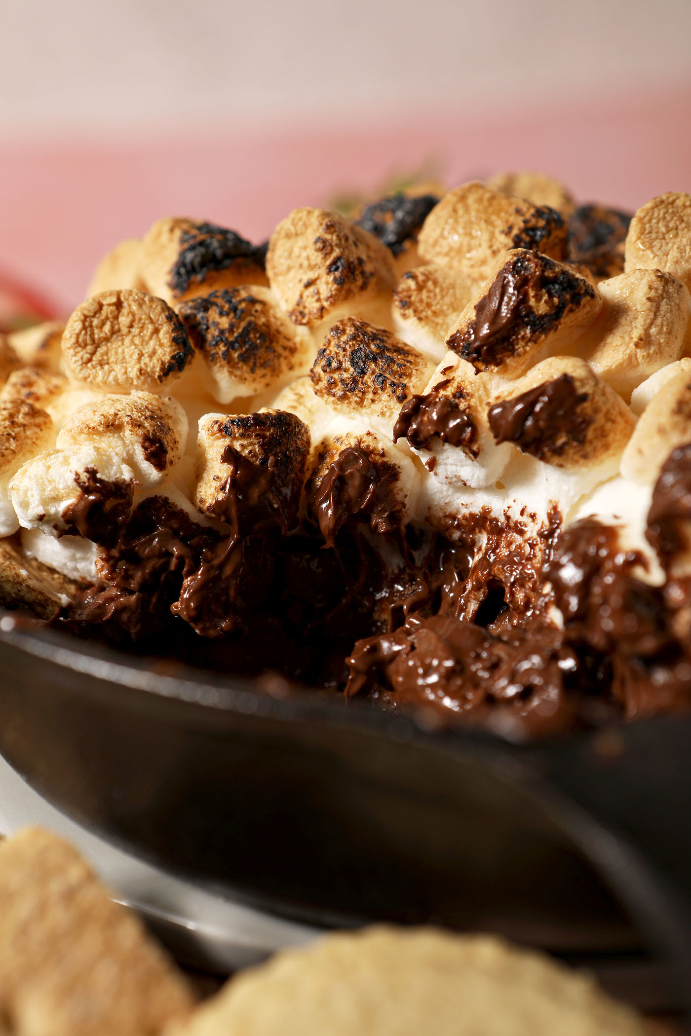 Close up of melty s’mores dip in a skillet with toasted marshmallows on top