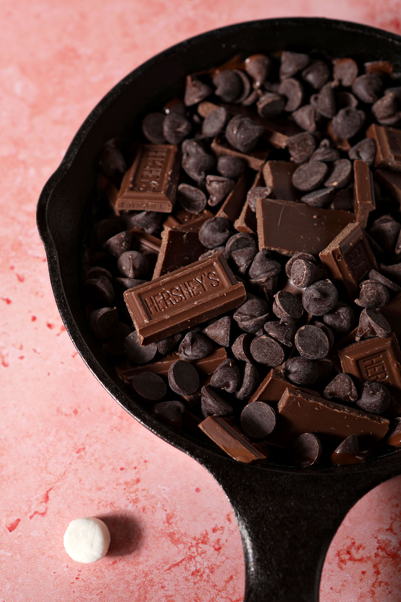 Chocolates in cast iron skillet on a pink surface