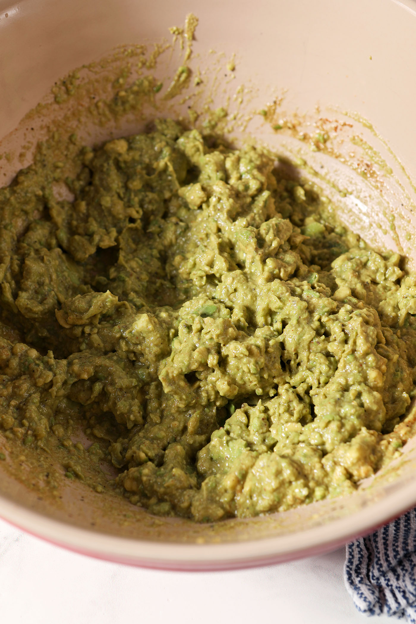 Smashed avocados in a bowl before mixing with coleslaw mix