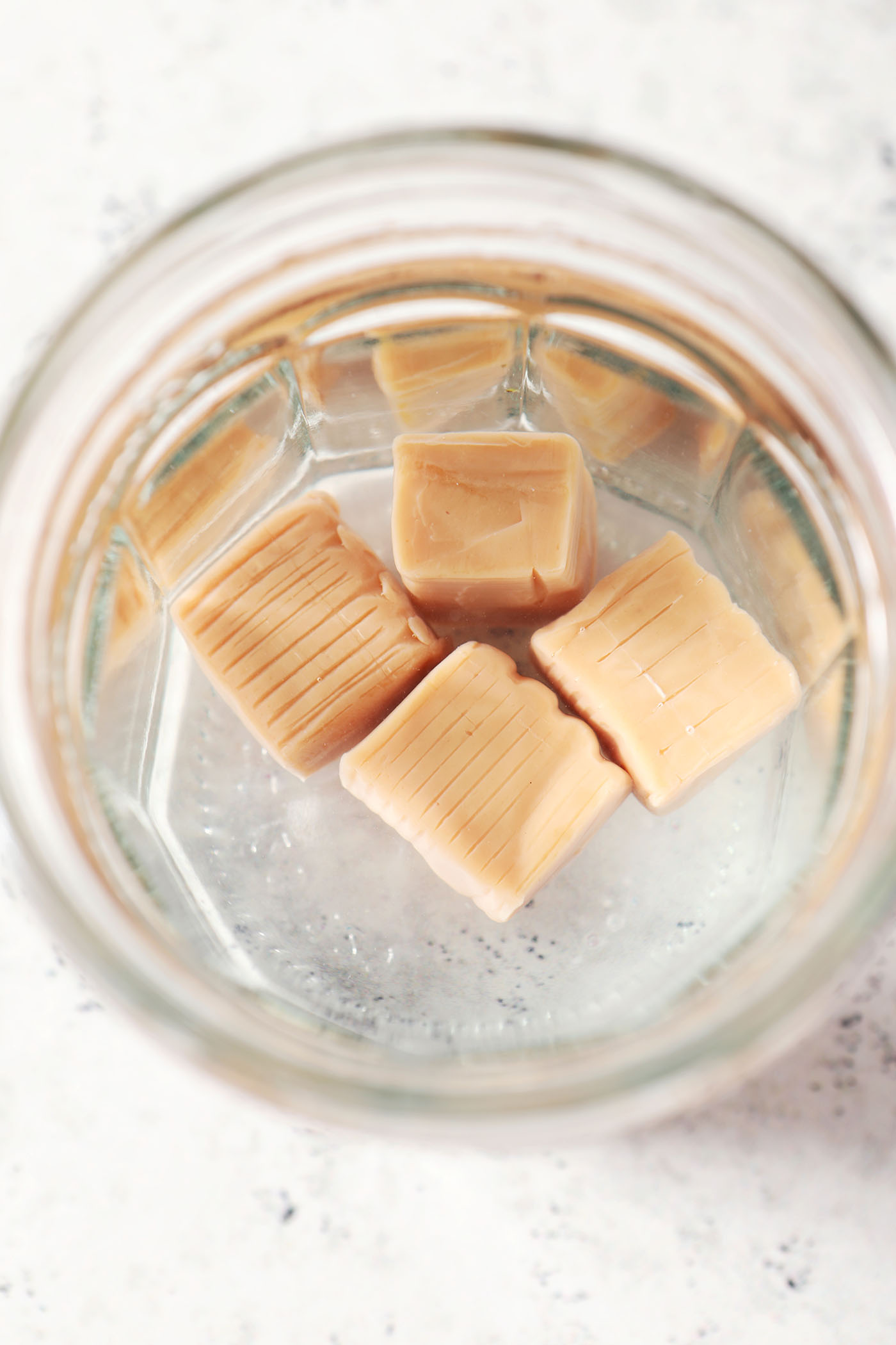 Close up of caramels dissolving in vodka in a glass jar